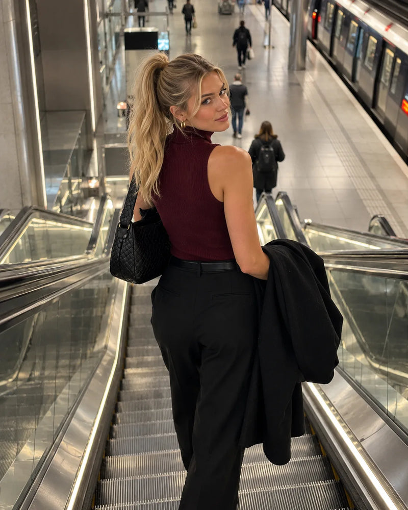 Vrouw in bordeaux mouwloze top op een roltrap
