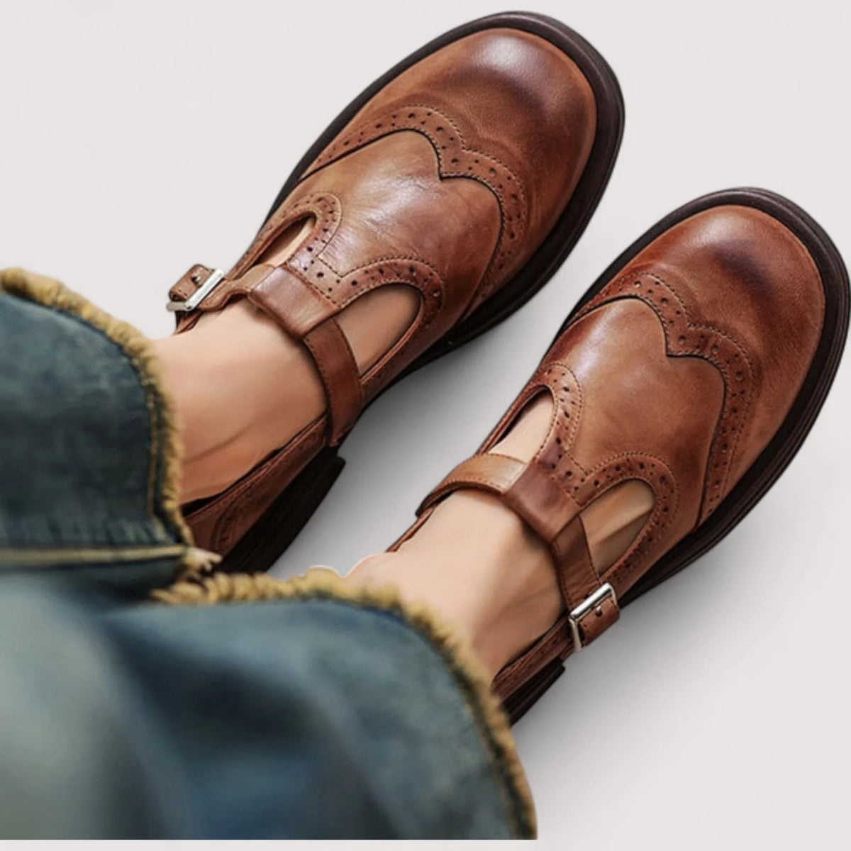 Bruine T-bandschoenen van bovenaf gezien, gedragen met jeans