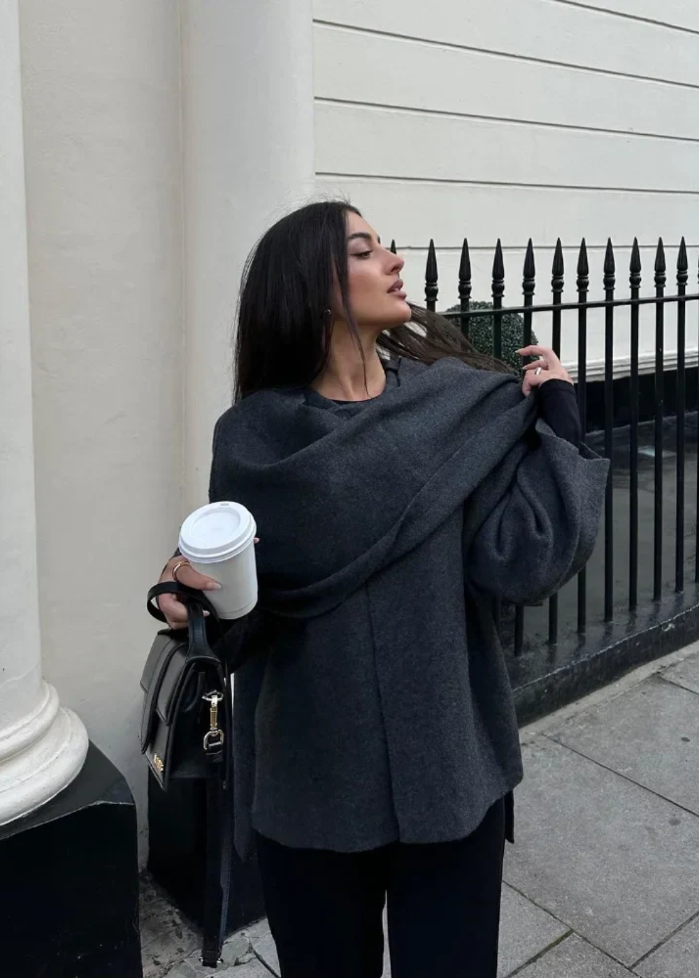 Oversized capejas dames met geïntegreerde sjaal in donkergrijs, gedragen met koffie in de hand