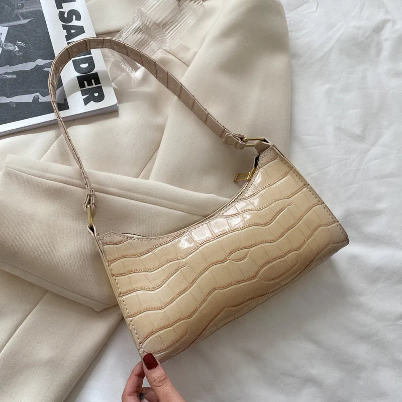 Beige compacte schoudertas met krokodillenreliëf in de hand gehouden