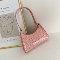 Roze compacte dames schoudertas met krokodillenprint en kort hengsel