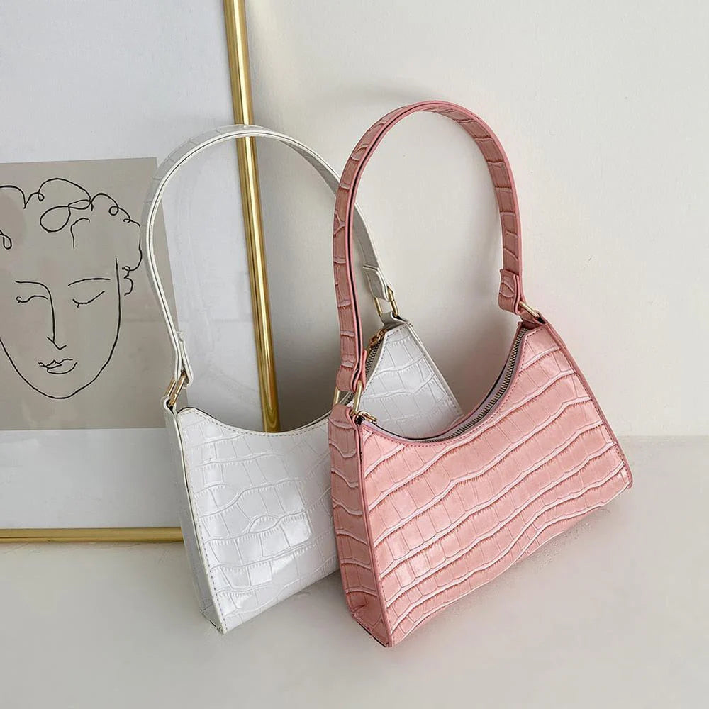 Witte en roze compacte dames schoudertassen met krokodillenprint naast elkaar