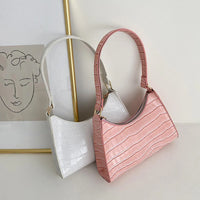 Witte en roze compacte dames schoudertassen met krokodillenprint naast elkaar