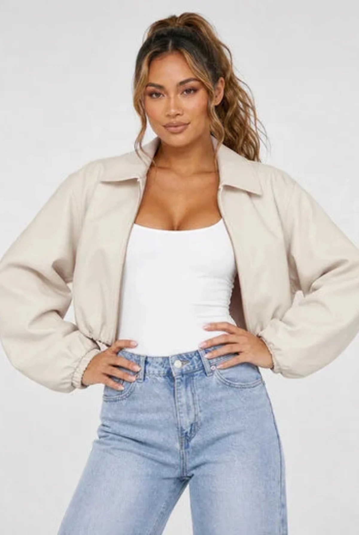 Crèmekleurige cropped dames jas met ballonmouwen en klassieke kraag op een lichte jeans