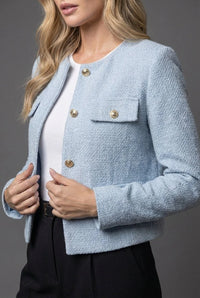 Detail van gouden knopen en klepzakken op lichtblauwe cropped blazer