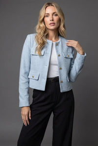 Lichtblauwe cropped dames blazer met tweedlook en gouden knopen op een zwarte broek