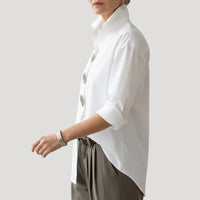 Witte blouse van opzij met de diagonale knopenlijn zichtbaar