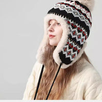 Vrouw met zwarte gebreide oorflapmuts met Fair Isle-motief en pluche voering