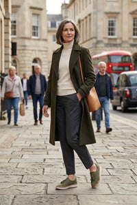 Vrouw op straat in de stad met instapsneakers en een lange jas