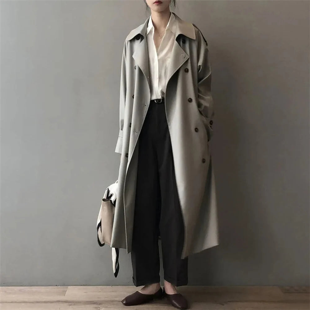 Model draagt een grijze lange dames trenchcoat met dubbele knoopsluiting