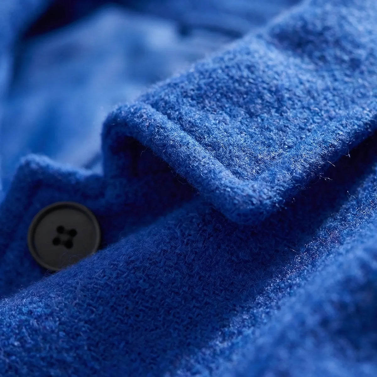 Detailfoto van de stof en de knoop van de blauwe mantel