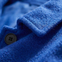 Detailfoto van de stof en de knoop van de blauwe mantel