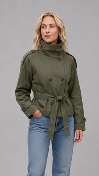 Korte trenchcoat dames in legergroen gedragen op een blauwe jeans