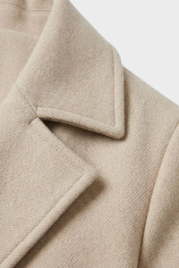 Detail van de reverskraag van de lange dames mantel in beige