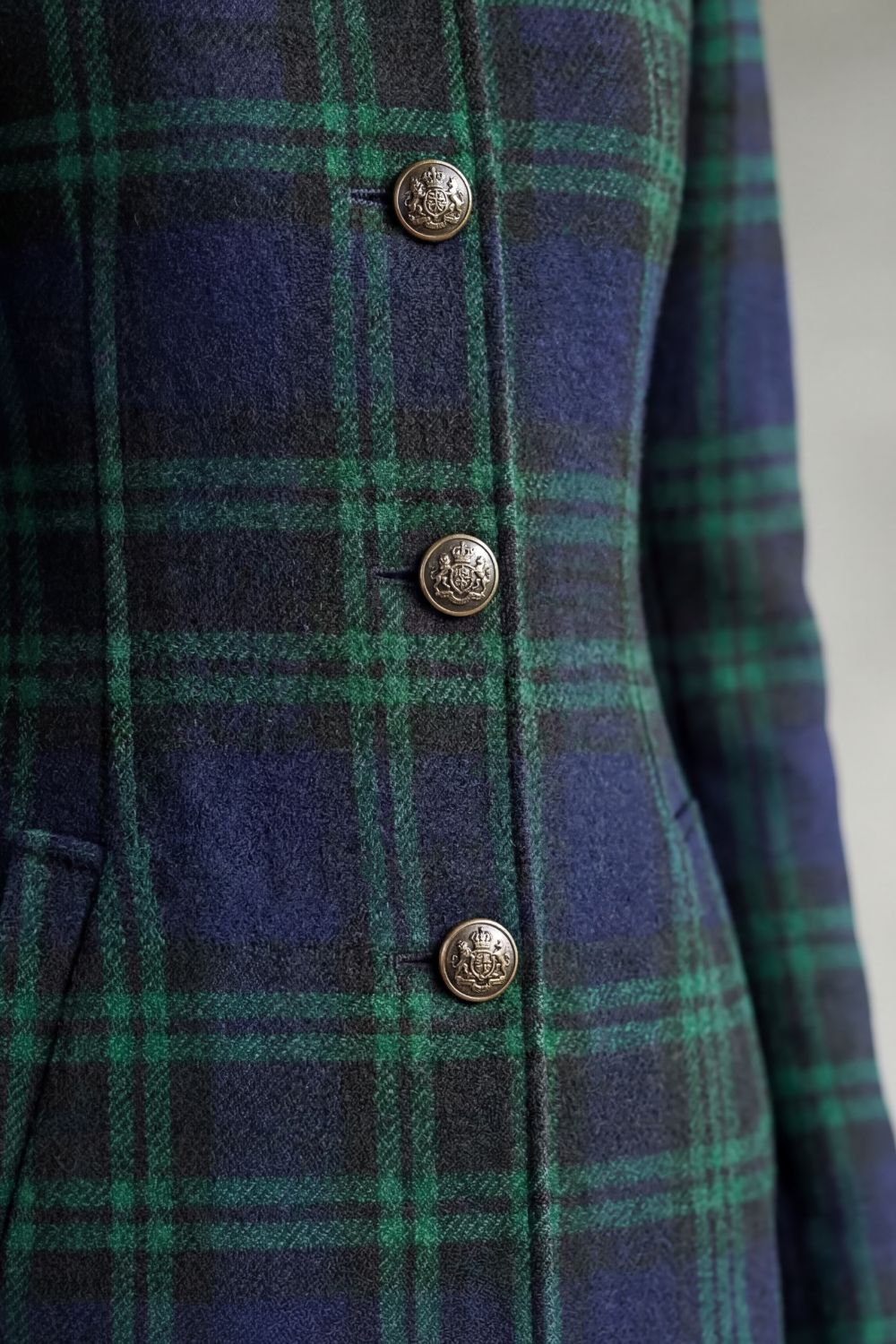 Detail tartan mantel blauwgroen: metalen knopen met reliëf en ruit van dichtbij
