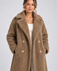 Close-up van taupe teddy jas met reverskraag en dubbele knopenrij