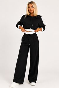 Zwarte loungeset dames met cropped hoodie, witte contrastrand en wijde broek, vooraanzicht