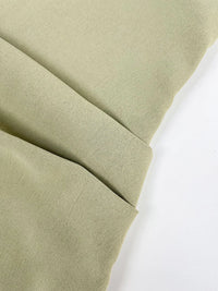 Detail van de plooien in de taille van de saliegroene jurk