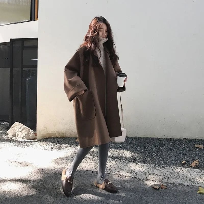 Bruine lange mantel dames oversized, gedragen met laarzen