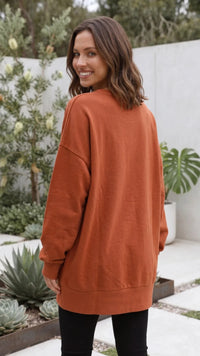 Achterkant van oranje oversized dames sweater met geribde boorden