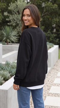 Achterkant van zwarte oversized dames sweater met geribde zoom