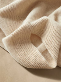 Detail van het zachte breisel en geribde boord van de poncho sjaal in beige