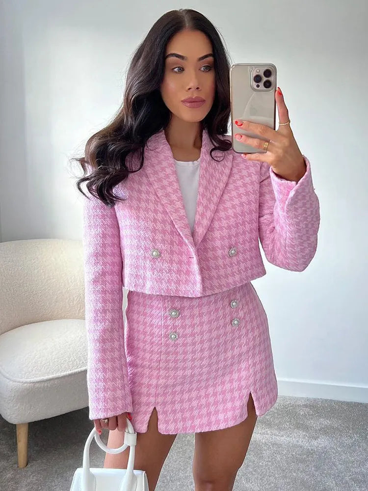 Vrouw in roze pied-de-poule blazerset met skort en witte top