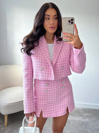 Vrouw in roze pied-de-poule blazerset met skort en witte top
