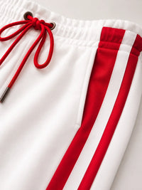 Detail van rode contraststreep op witte trainingsbroek dames