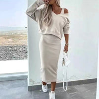 Vrouw in beige tweedelige rokset met V-hals sweater en midi kokerrok