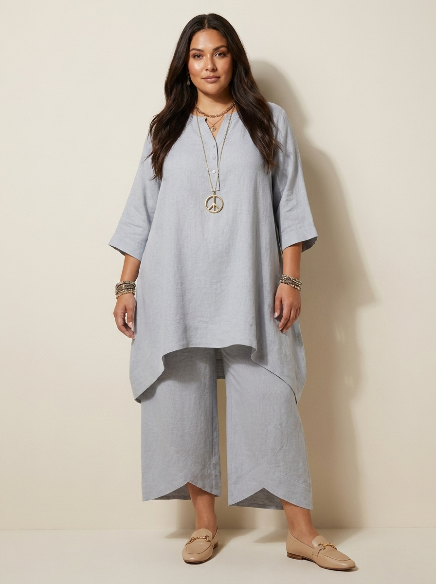Vrouw in lichtgrijze tweedelige set met lange asymmetrische tuniek en losse broek, vooraanzicht